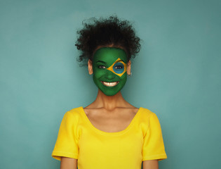Young woman with Brazil flag painted on her face