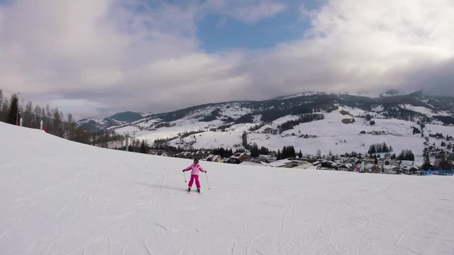 Little girl skiing with a beautiful view on a village in mountains