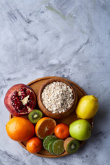 Bowl with oatmeal flakes served with fruits on wooden tray over white background, flat lay, selective focus