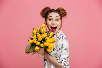 Portrait of an excited young girl holding yellow tulips