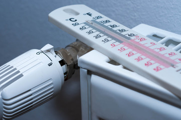 Thermometer on white radiator close up shot , heater knob indicates the full power.
