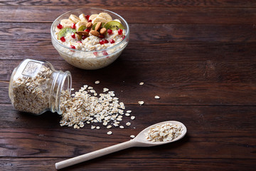 Composition with bowl of oatmeal porrige and dry oatmeal in glassware on vintage wooden table, selective focus