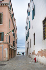 People walking down a typical small narrow street of old town Venice leading to Fondamente Nove by the lagoon
