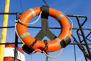 Orange life ring hanging on ship deck against the sky
