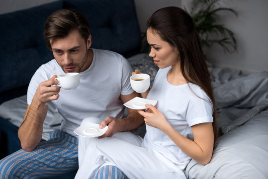 Young Couple In Loungewear Drinking Coffee In Bed