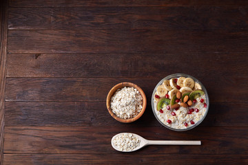Diet breakfast oatmeal with fruits, bowl and spoon with oat flakes, selective focus, close-up