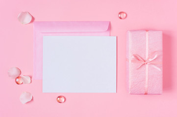 Blank postcard and gift box decorated with bow on pink