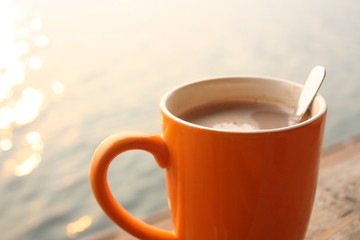 Morning hot coffee on wood table and water background