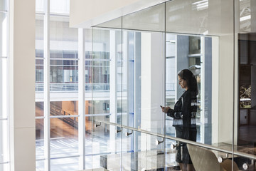 Businesswoman standing in a conference room window in a large business centre.