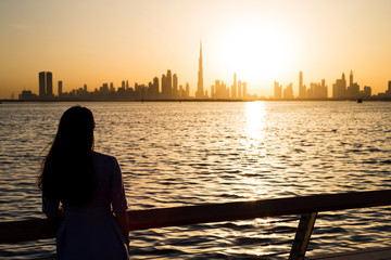 Fototapeta premium Woman facing panoramic view of Dubai at sunset