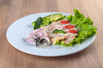 1.	herring fillet with onion, chili pepper and avocado is laid out on a leaf of green salad
