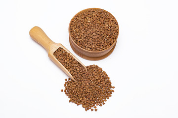Buckwheat in a wooden bowl and in a wooden scoop on a white background.