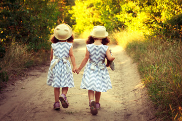 Back view of little girls sisters twins holding hands. Love, happy , friendship and future concept