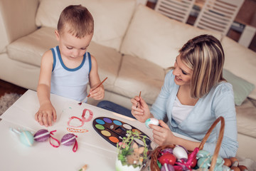 Mother and her son painting eggs