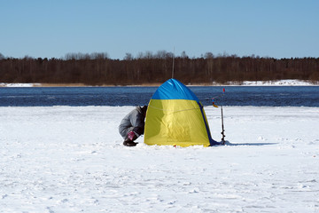 Winter fishing on the edge of the ice. A fisherman with a tent.