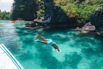 Man jumping into clear sea water in Asia - obrazy, fototapety, plakaty