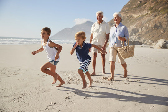 Grandparents Running Along Beach With Grandchildren