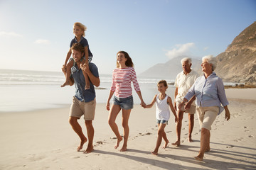 Multi Generation Family On Vacation Walking Along Beach Together