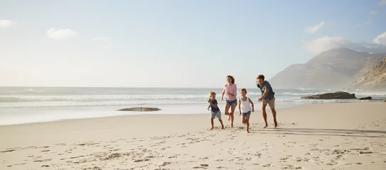 Fototapeten Parents Running Along Beach With Children On Summer Vacation © Monkey Business
