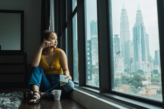 Woman looking through window while sitting at home