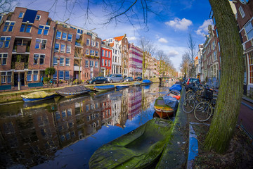 Beautiful outdoor view of houses and Boats on Amsterdam Canal with frozen river, morning photo of colored houses in the Dutch style with reflection in water