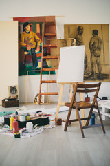 Painting studio interieour. Easer, chair, colors and paintings all around.