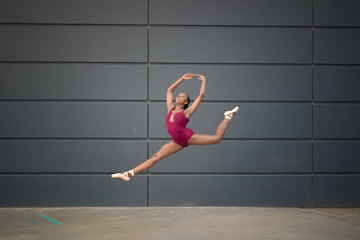 Girl wearing a leotard and ballet slippers and leaping