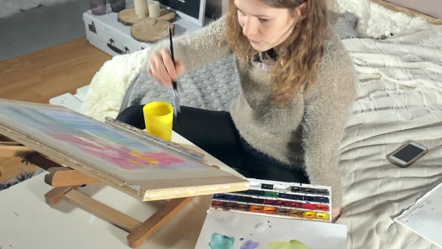 Adult women paint with colored watercolor paints in an art school