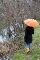 femme avec un parapluie marchant au bord d'une rivière dans la grisaille