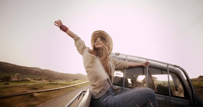 Beautiful woman sitting with outstretched arms in a pick-up truck