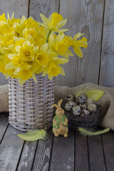 Easter composition: rabbit, quail eggs in the nest and narcissus in the basket