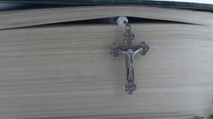 Bible and rosary. Closed holy book with a hanging cross from the rosary