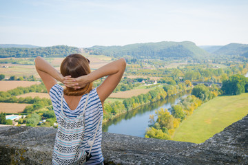 Summer vacation. Girl with a backpack raised her hands up. Beautiful rural landscape. tourist girl enjoys a beautiful view of the valley. Silence and rest, time to rest, the best view.
