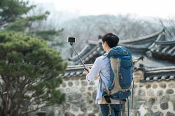 A young man who travels to Korea is taking pictures using his smartphone.