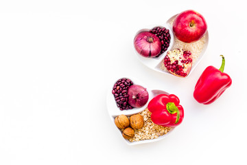 Diet for healthy heart. Food with antioxidants. Vegetables, fruits, nuts in heart shaped bowl on white background top view copy space