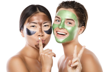 Two beautiful girls with colorful peel-off masks on their faces
