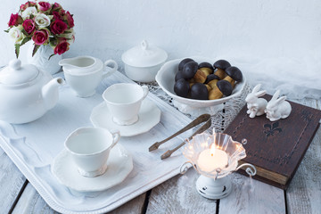 on white table kettle, cup, sugar bowl, book, candle and biscuits in the form of mushrooms