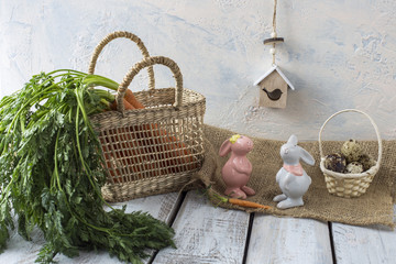 on a white wooden table fresh carrots, two rabbits, quail eggs and a birdhouse