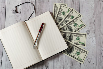 Notepad, pen and money on a light wooden background