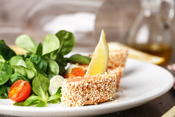 salad with salmon grilled in sesame seeds, cherry tomatoes and quail egg on wooden table