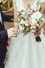 Wedding decor, flowers, rings, bouquet in the hands, rings, groom and bride