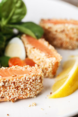salad with salmon grilled in sesame seeds, cherry tomatoes and quail egg on wooden table