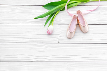Ballet shoes near delicate flowers on white wooden background top view copy space