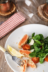 salad with salmon grilled in sesame seeds, cherry tomatoes and quail egg on wooden table