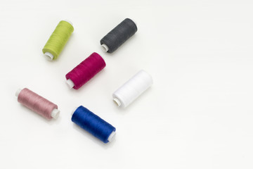 Colored thread coils on white background, sewing, place for text