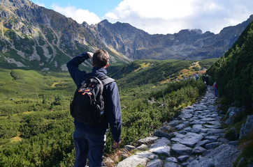 Turysta górski patrzący na grań Orlej Perci ze szlaku niebieskiego do czarnego Stawu Gąsienicowego