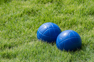 Blue bocce balls on lush green grass with a very shallow depth of field and copy space