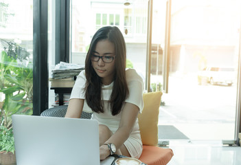 Fototapeta premium Beautiful asian attractive woman has working and typing on laptop computer for business marketing at coffee cafe in the morning with happy and relaxing time.