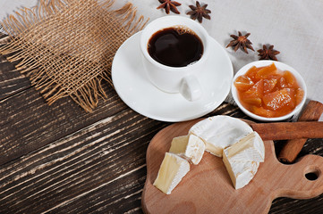 Food - a cup of hot coffee, soft light cheese covered with white mold on an old wooden background.