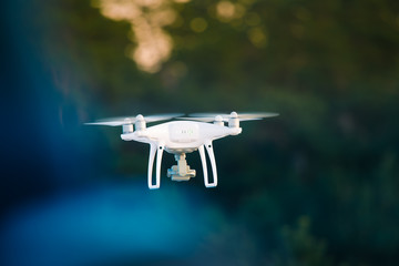 A beautiful flying drone in the evening skies. Aero photography in action. White drone flying.
